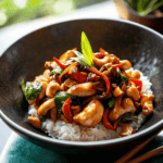 A sizzling wok filled with authentic Thai Cashew Chicken stir-fry featuring tender chicken, perfectly toasted cashews, vibrant bell peppers, and fresh green onions.