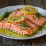 Close-up view of golden-baked salmon fillets garnished with fresh lemon slices and herbs, highlighting a flavorful dish.