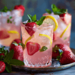 Glasses of Love Potion Pink Lemonade garnished with strawberry, lemon, and mint