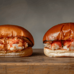 Two mouthwatering Maine Lobster Rolls overflowing with lobster salad on toasted split-top buns, garnished with paprika.
