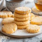 Golden and crumbly shortbread cookies on a white plate, perfect for tea time.