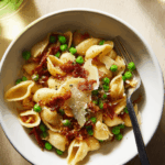 Served plate of pasta with bacon and peas