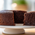 Whole gluten free chocolate cake with a cut slice.