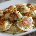 Golden pan-fried pierogi with butter and onions.
