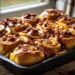 Golden Bourbon Maple Cinnamon Rolls with glaze and bacon bits.