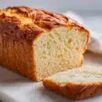 A golden loaf of sliced Gluten free bread recipe on a wooden board.