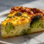 Golden slice of impossible broccoli pie on a rustic wooden board