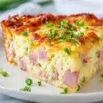 Golden brown slice of impossible ham and cheese pie on a ceramic plate