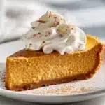 A slice of impossible pumpkin pie showing the self-forming crust layer on a rustic wooden board.