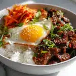 A steaming bulgogi rice bowl recipe with caramelized beef, egg, and kimchi