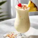 A thick, creamy frozen pina colada recipe topped with a cherry and pineapple wedge.
